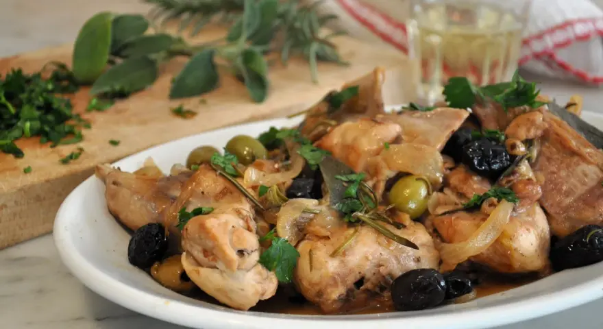 Un saporito coniglio alla cacciatora in bianco, con olive verdi e nere, cipolle e rosmarino, pronto per essere gustato.