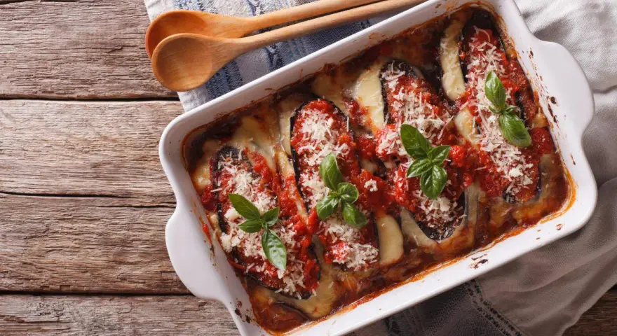Parmigiana di melanzane appena sfornata, con melanzane, pomodoro, mozzarella filante e basilico fresco.