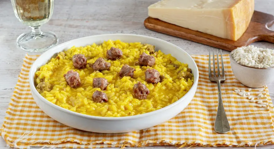 Un invitante risotto alla monzese, giallo intenso e arricchito da pezzetti di salsiccia, pronto per essere gustato.