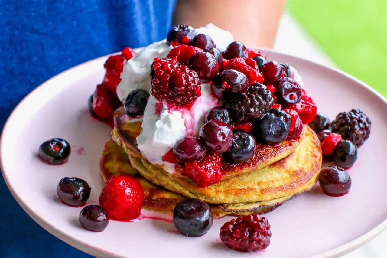 Pancake proteici con panna e frutti di bosco freschi, una deliziosa ricetta per iniziare la giornata con energia.