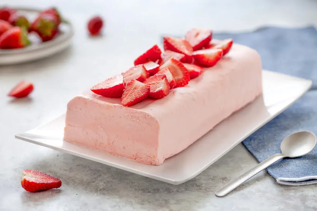 Delizioso semifreddo rosa decorato con fragole fresche, un dolce estivo perfetto.