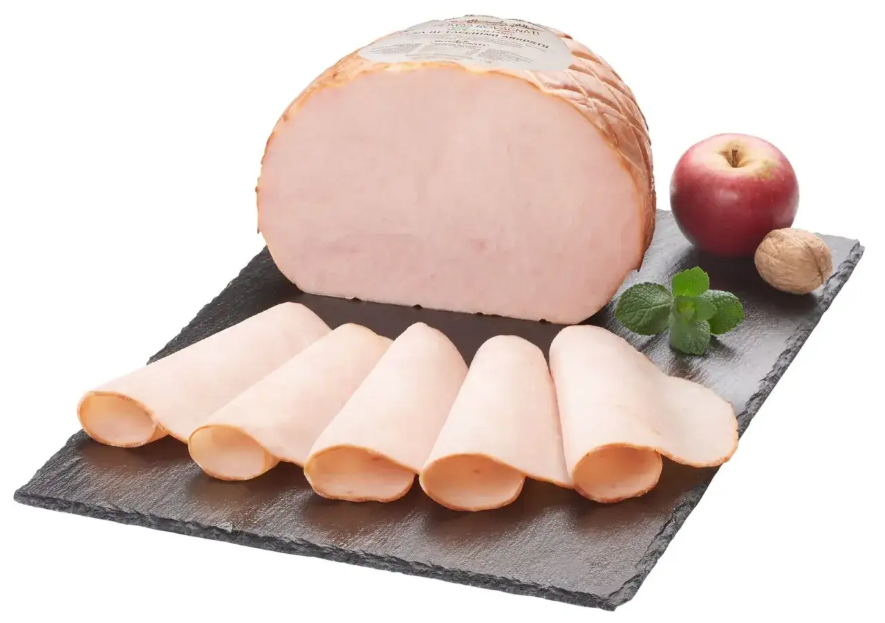 Un succulento arrosto di tacchino affettato, servito su una pietra scura con mela, noce e menta.