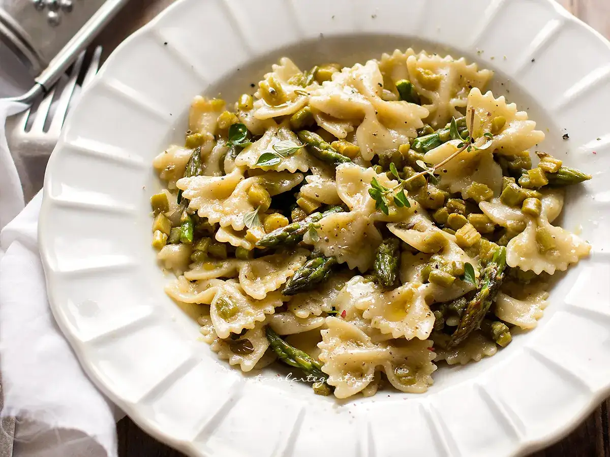 Farfalle condite con asparagi freschi e un filo d'olio, guarnite con erbe aromatiche. Un piatto leggero e gustoso.