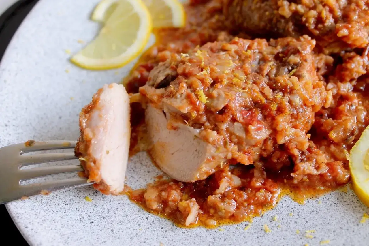 Un saporito ossobuco di tacchino in umido con pomodoro e riso, guarnito con scorza di limone e spicchi freschi.