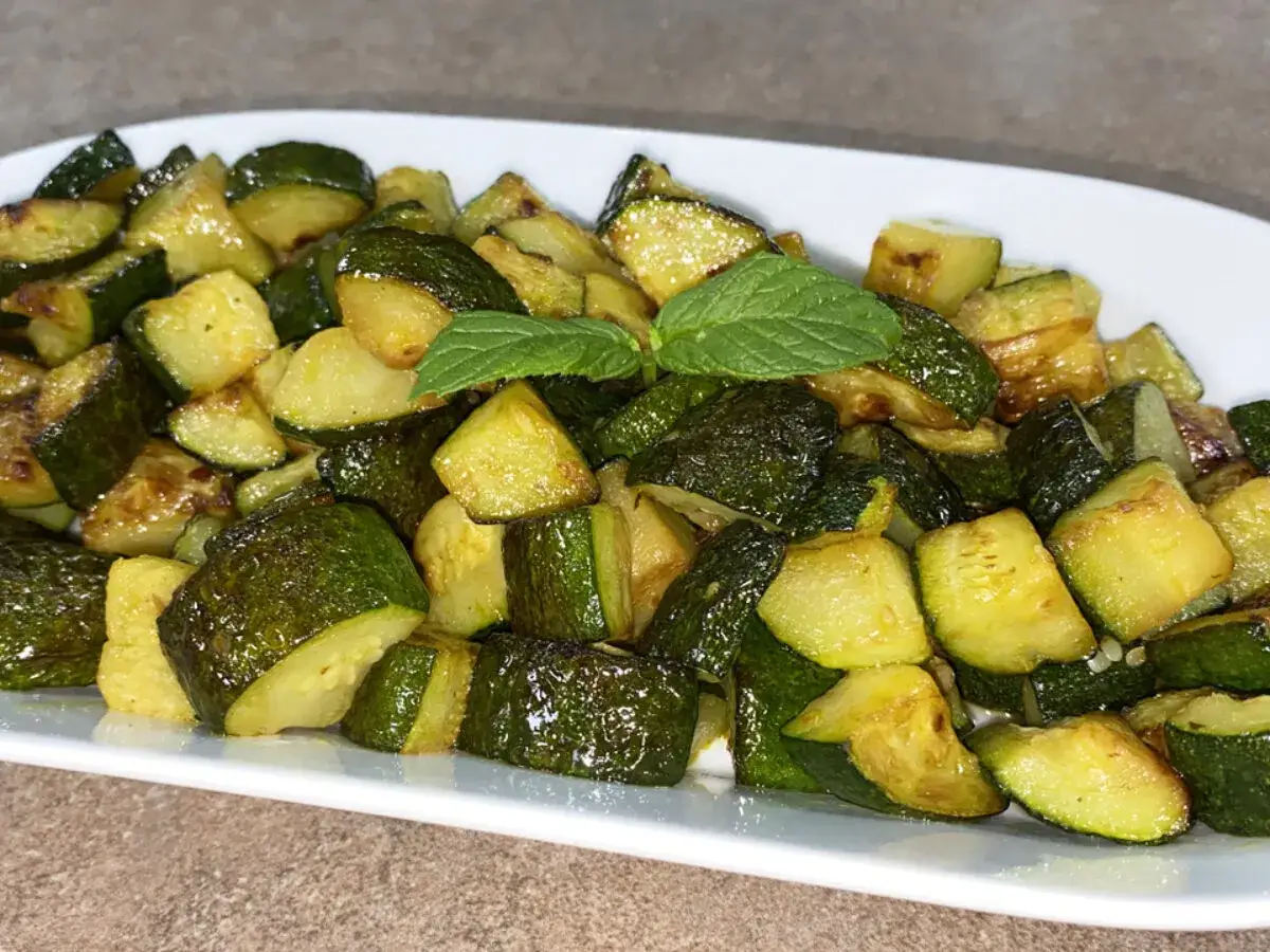 Zucchine in padella, tagliate a cubetti e dorate, guarnite con foglie di menta fresca. Un contorno saporito e leggero.