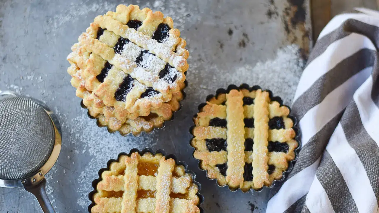 Tre crostatine di pasta frolla con olio, ripiene di marmellata, spolverate di zucchero a velo.