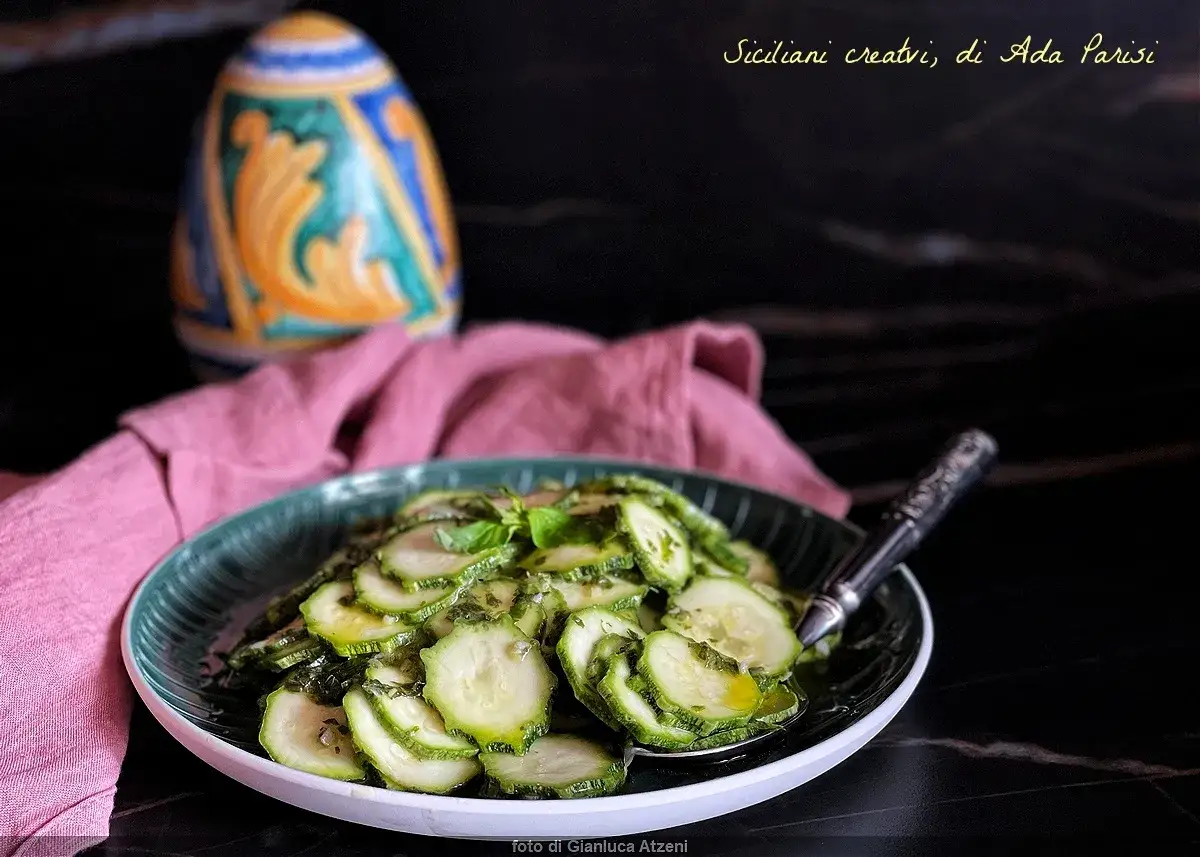 Fette di zucchine marinate crude, condite con erbe aromatiche e olio. Un piatto fresco e leggero, perfetto per l'estate.