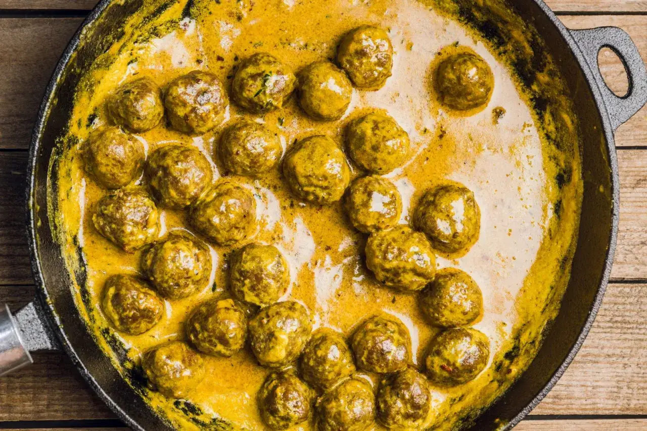 Polpette in bianco cremose in padella, dorate e succulente, immerse in una salsa gialla e vellutata.