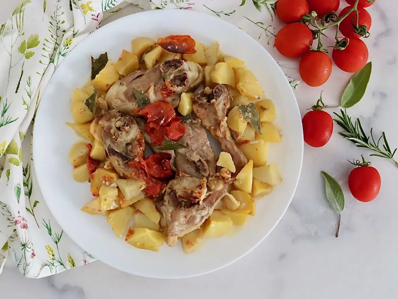 Agnello al forno con patate e pomodorini, un piatto saporito e profumato, pronto per essere gustato.