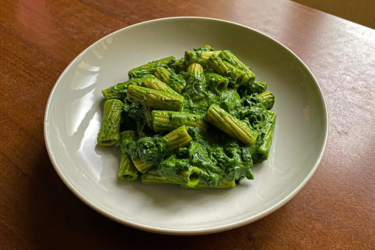Piatto di pasta con spinaci cremosa, un classico della cucina italiana, servita su un piatto bianco.
