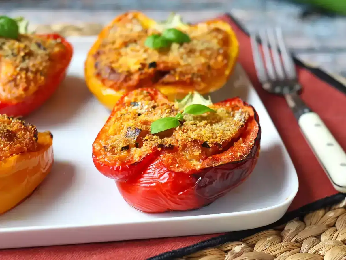 Peperoni ripieni senza carne, dorati e invitanti, guarniti con basilico fresco. Un piatto vegetariano gustoso e colorato.