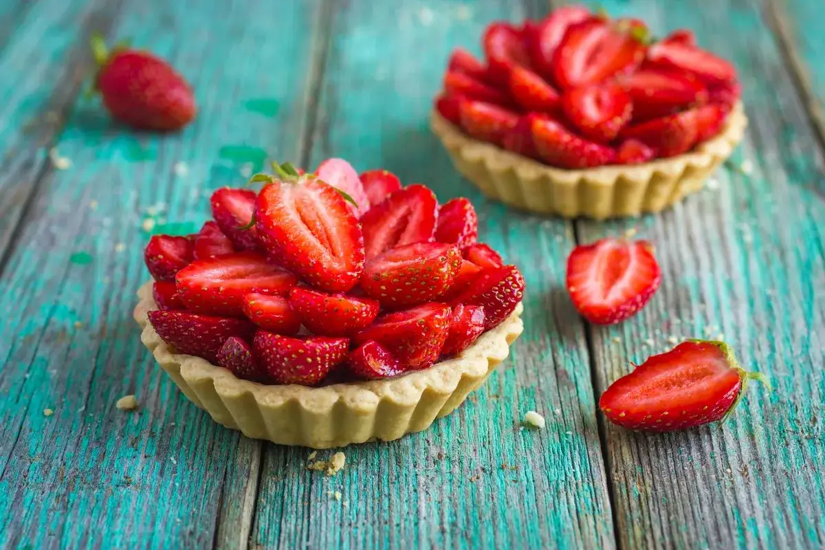 Deliziosi dolci con fragole fresche, disposti su un tavolo di legno turchese.