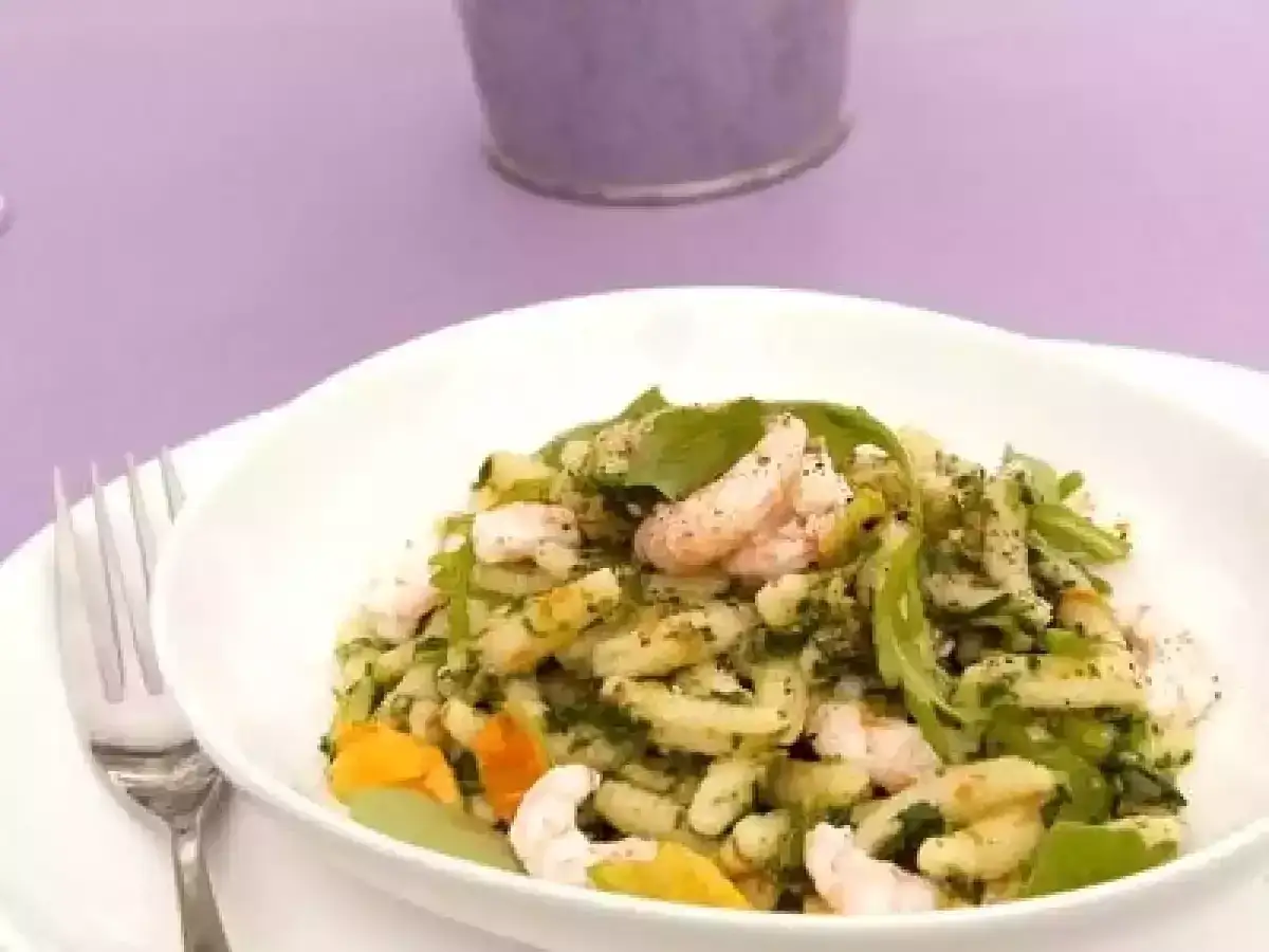 Un piatto invitante di pasta con gamberetti, condita con erbe fresche e un tocco di arancia.