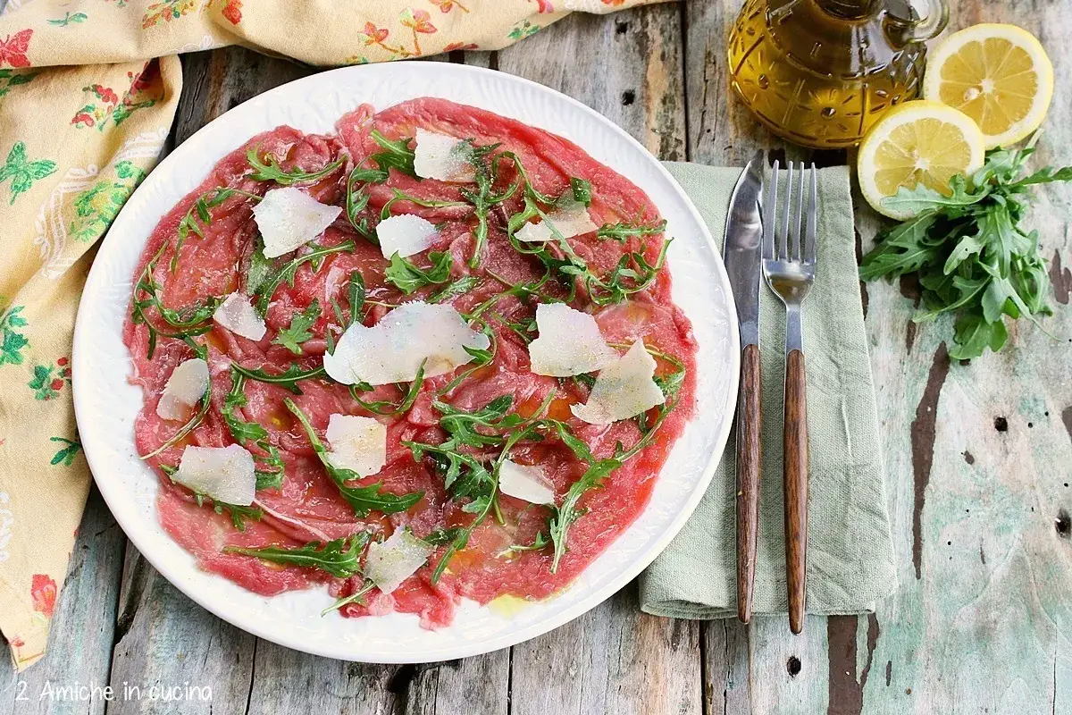 Delizioso carpaccio di manzo con rucola e scaglie di parmigiano, condito con olio d'oliva e limone.