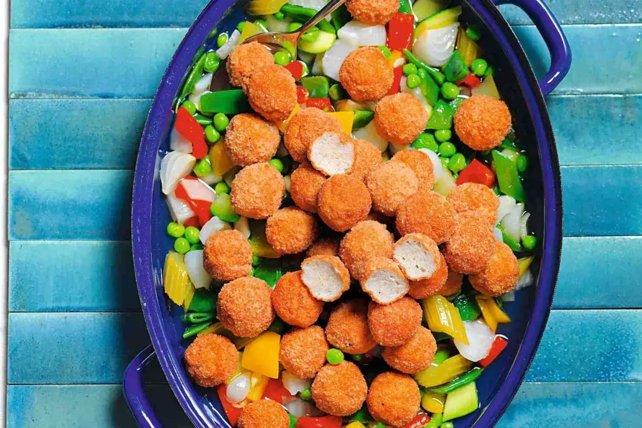Piatto di verdure miste con polpette dorate di petto di pollo, un pasto colorato e invitante.