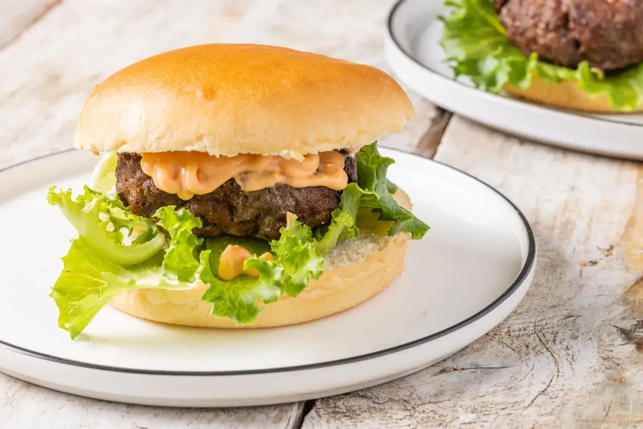 Hamburger succulento con salsa, lattuga e panino soffice, preparato in friggitrice ad aria.