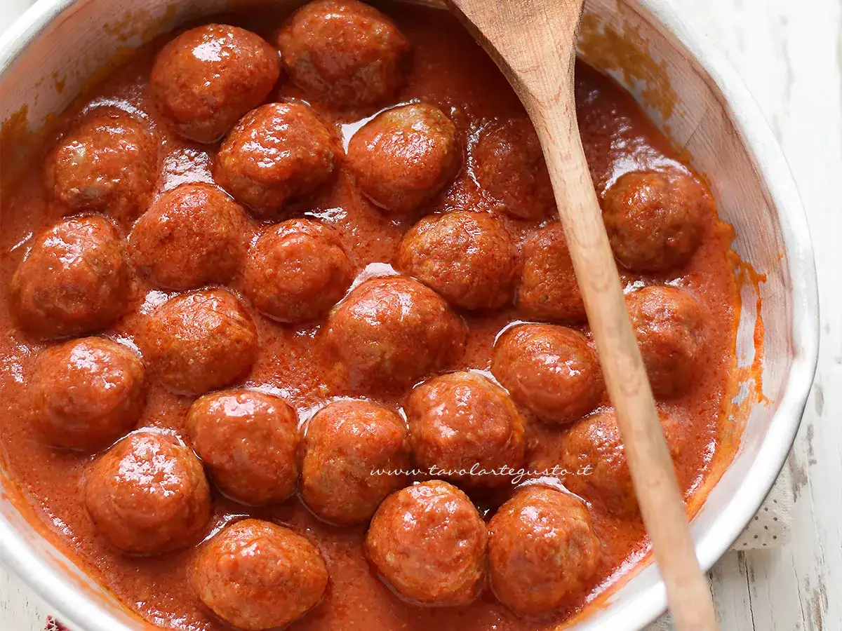 Succulente polpette in padella, immerse in un sugo rosso invitante, pronte per essere gustate.