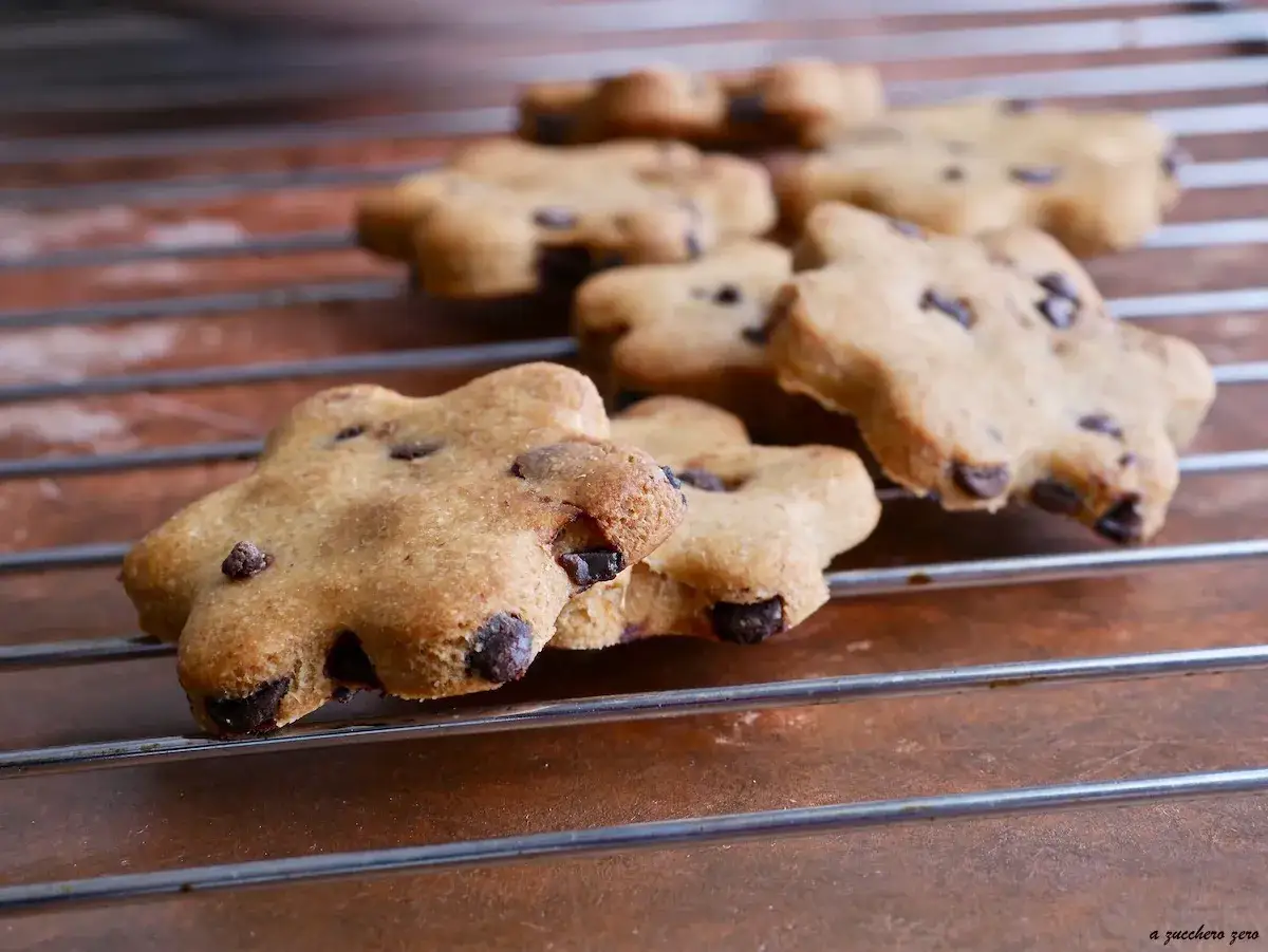 Biscotti senza zucchero a forma di fiore con gocce di cioccolato, appena sfornati e raffreddati su una griglia.