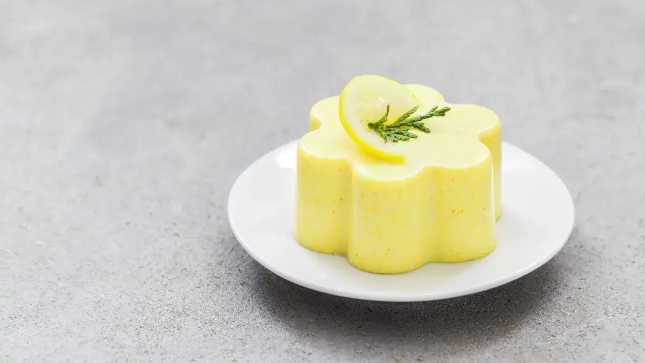 Delizioso budino fatto in casa a forma di fiore, guarnito con una fetta di limone e un rametto verde.