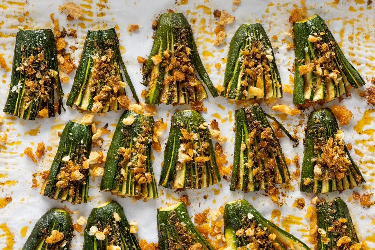 Zucchine al forno tagliate a metà, condite con pangrattato croccante e spezie, pronte per essere gustate.