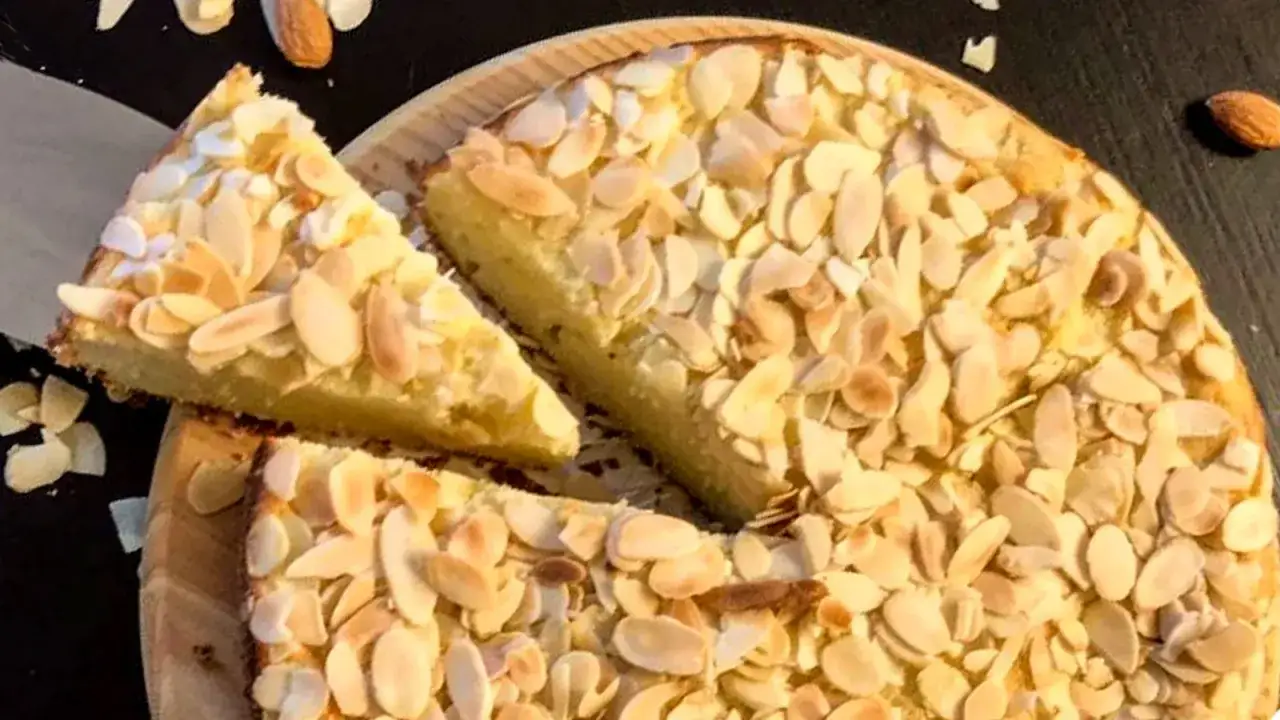 Torta con farina di mandorle, ricoperta di mandorle a lamelle tostate. Una fetta &egrave; stata tagliata e posizionata sopra.