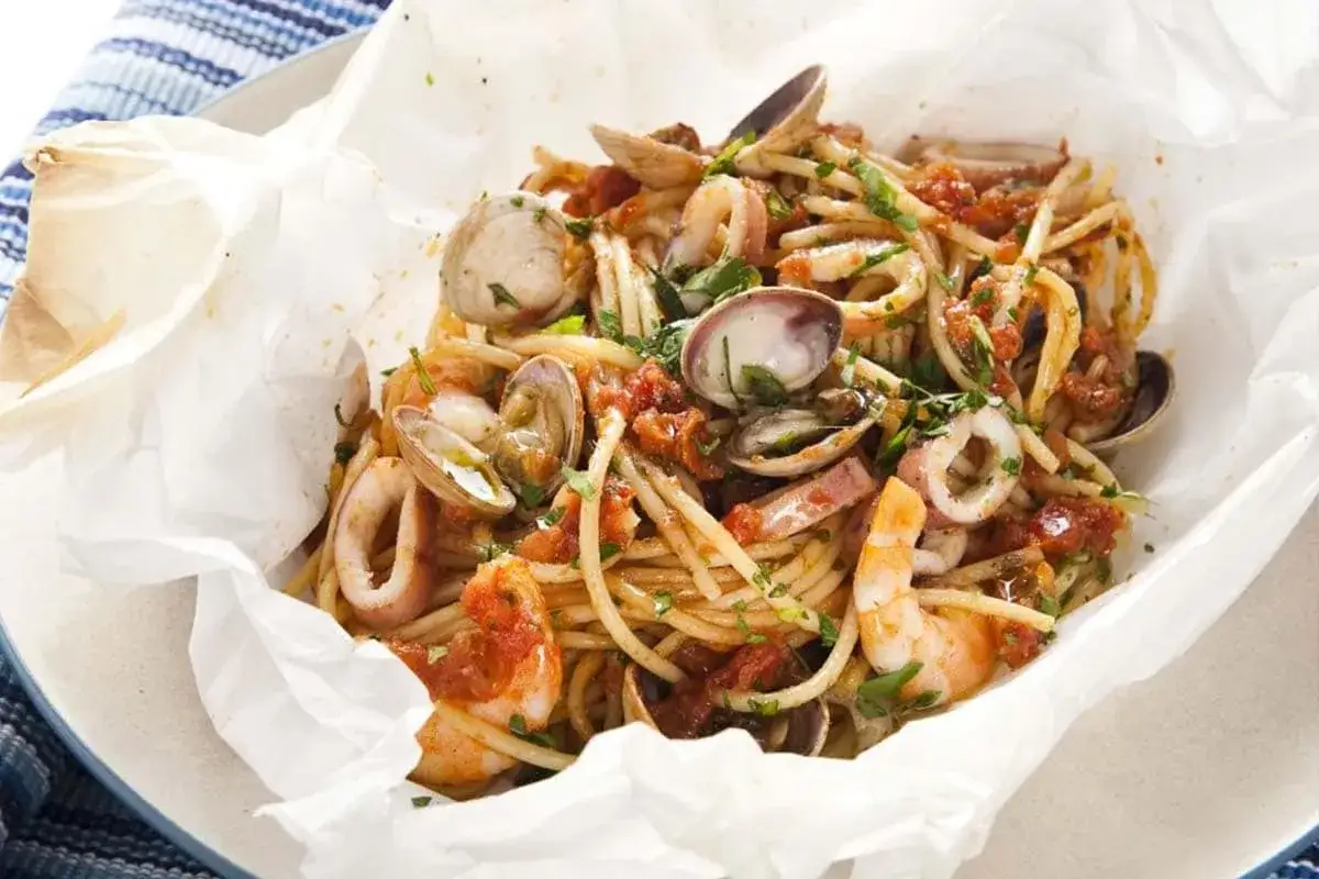 Spaghetti con vongole, gamberi e anelli di calamaro, conditi con pomodoro e prezzemolo. Un piatto che ricorda la carbonara di mare.
