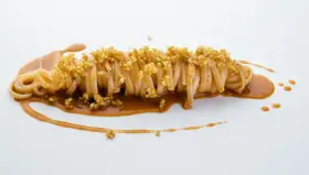 Pasta con carciofi Cannavacciuolo, un piatto elegante con pasta lunga, salsa cremosa e croccanti germogli di quinoa.