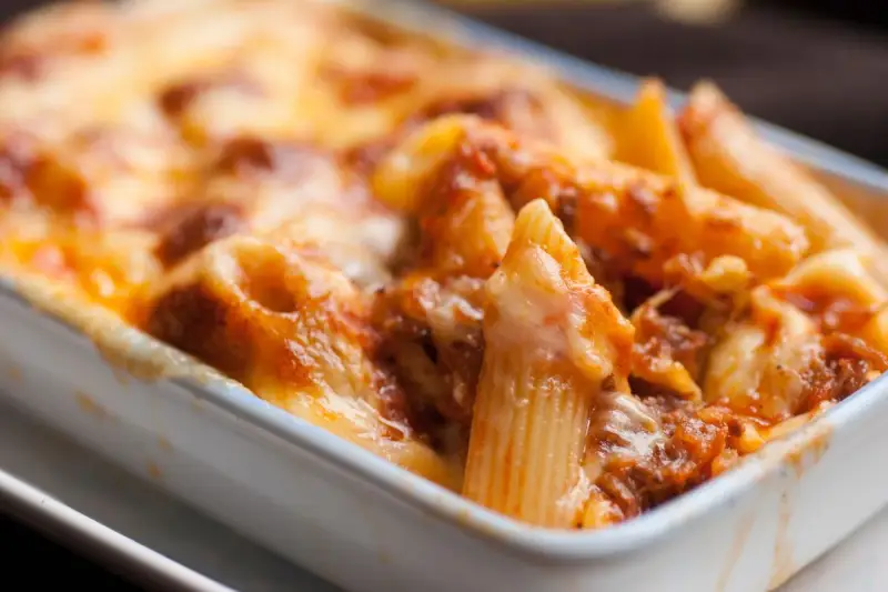 Penne al forno con sugo di pomodoro e mozzarella filante, un classico della pasta alla sorrentina.