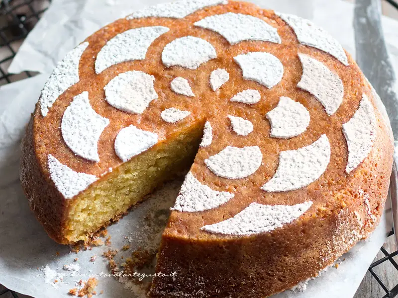 Torta soffice caprese al limone, decorata con zucchero a velo a forma di fiore.